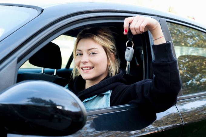 young-girl-happy-holding-car-key-seated-in-her-new-car